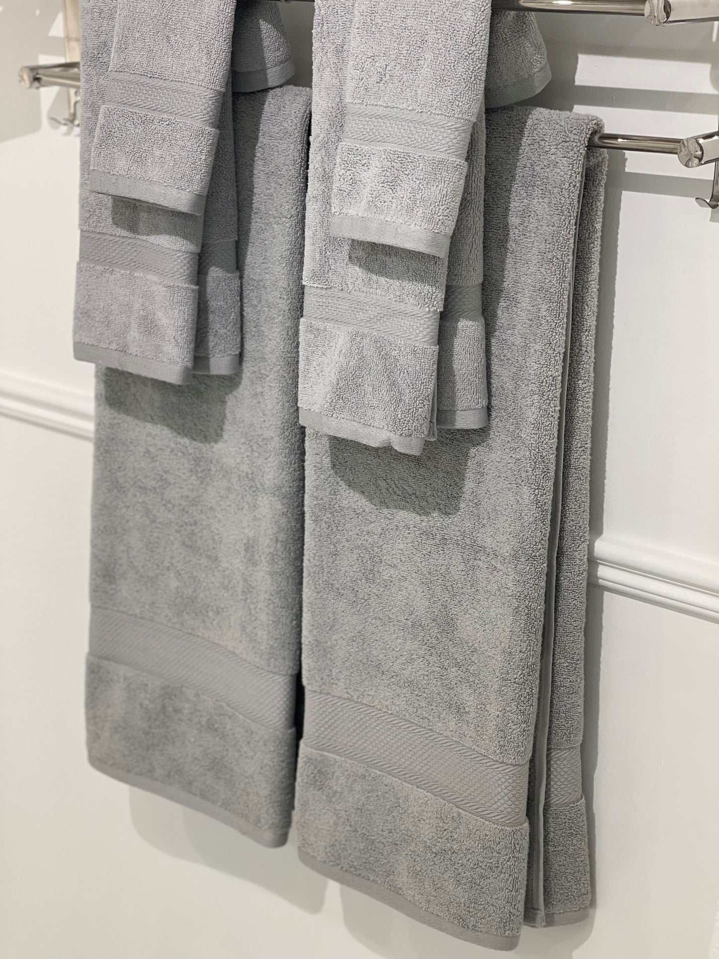 six gray towels hung on a rack