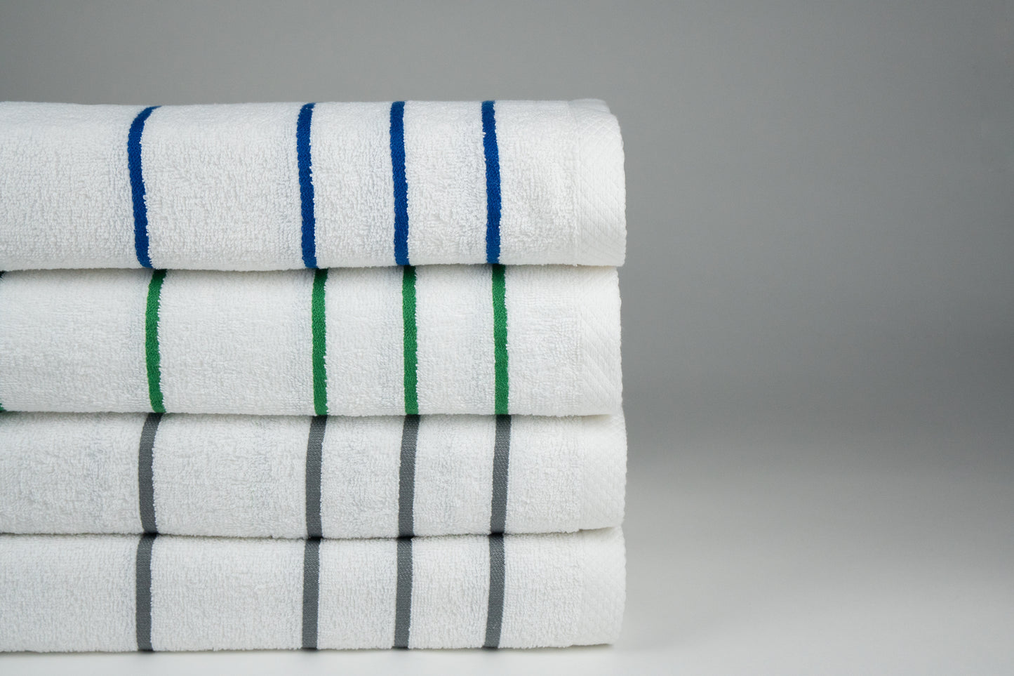 stack of four pool towels close up, one blue one green two grey