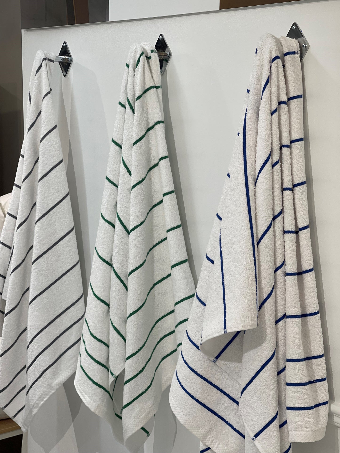 three pool towels hung, one gray one green one blue
