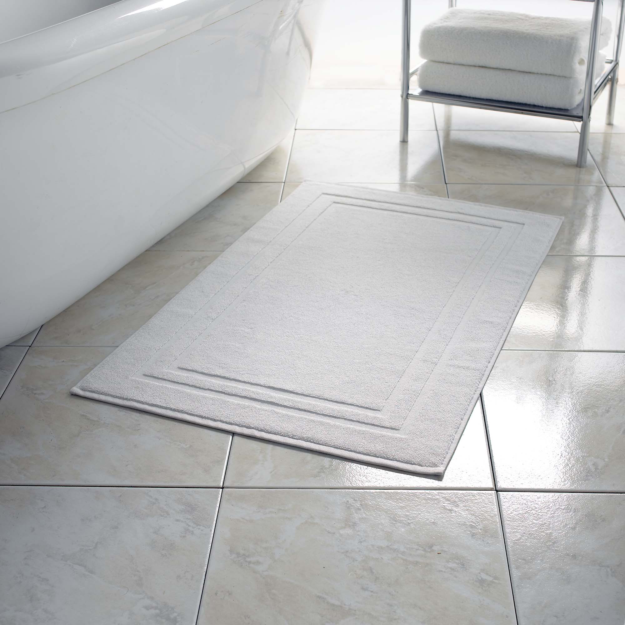 white floor towel next to bath tub