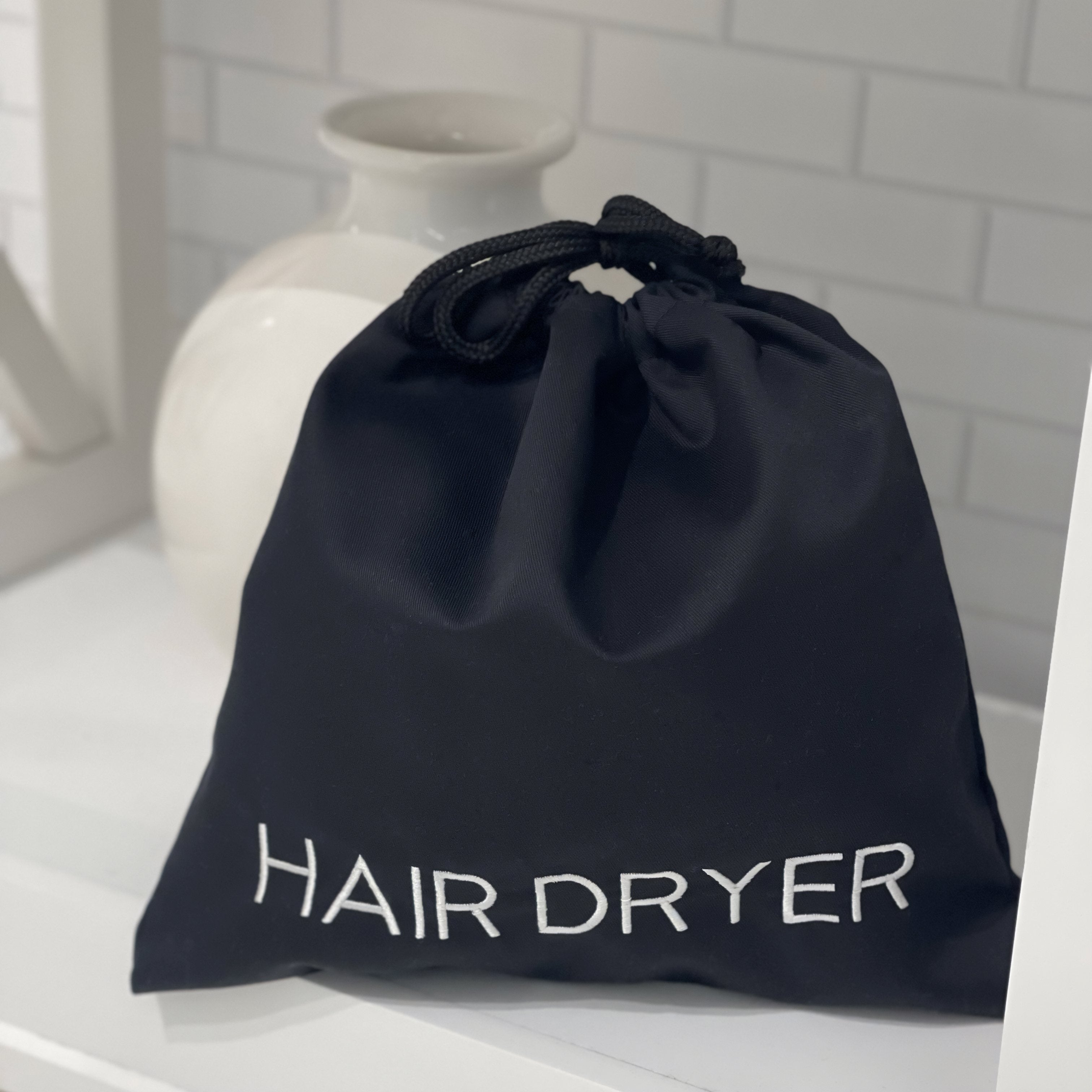 black hair dryer bag labeled with white text
